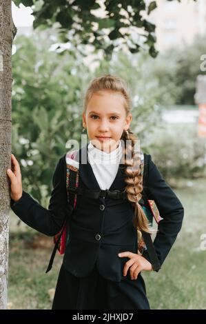 Zurück zur Schule. Kleine glückliche Kind Schüler Schülerin acht Jahre alt in Mode-Uniform mit Rucksack und Frisur voluminösen langen Zopf bereit zu gehen Stockfoto