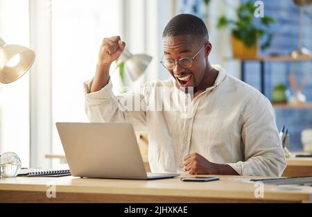 Er dachte nie, dass es passieren würde. Ein junger Geschäftsmann jubelte vor Aufregung an seinem Schreibtisch. Stockfoto