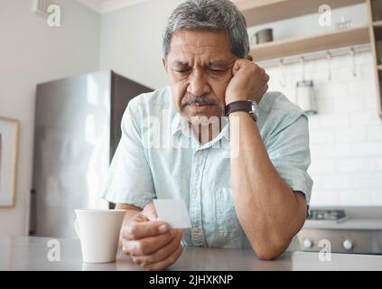 Es wird mit der Zeit besser. Ein älterer Mann, der unglücklich aussieht, während er zu Hause ein Foto ansieht. Stockfoto
