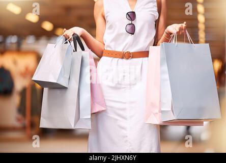 Beschnittene Nahaufnahme der weiblichen Hände, die während eines Einkaufsbummel Taschen tragen. Stilvolle Frau, die in einem Einkaufszentrum einkaufen und dabei gekaufte Artikel in der Hand hält. Schau dir an Stockfoto