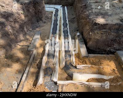 Verlegung eines Wasserrohrs in einen Graben im Boden mit Isolierung. Stockfoto