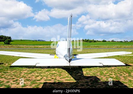 Ultraleichtes einmotorisches Flugzeug, das auf dem Flugplatz mit blauem Himmel und Feldhintergrund abheben soll Stockfoto