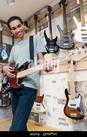 KIEW, UKRAINE - 16. FEBRUAR 2022: Lächelnder afroamerikanischer Kunde spielt E-Gitarre im Musikgeschäft Stockfoto