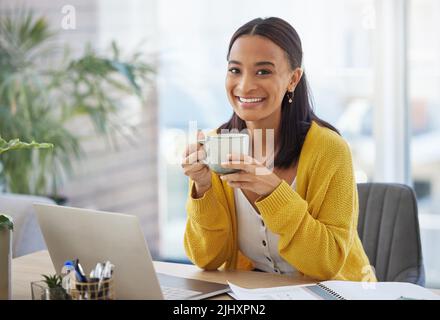 Kaffee vor der Arbeit. Eine junge Geschäftsfrau trinkt Kaffee in einem modernen Büro bei der Arbeit. Stockfoto