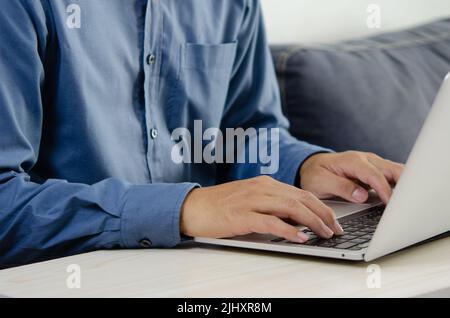 Geschäftsmann Hand Tastatur auf Laptop-Computer eingeben. Nahaufnahme des Geschäftsmannes, der an seinem Schreibtisch Internet und soziale Medien kommuniziert. Stockfoto