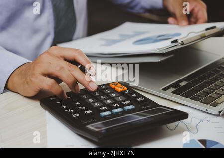 Businessman Holding Taschenrechner und Geschäftsdokumente Charts statistische Daten Investitionsanalyse und Steuerbuchhaltung. Stockfoto