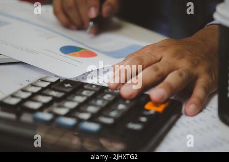 Businessman Holding Taschenrechner und Geschäftsdokumente Charts statistische Daten Investitionsanalyse und Steuerbuchhaltung. Stockfoto