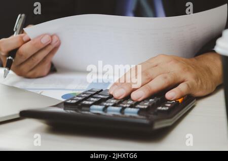 Businessman Holding Taschenrechner und Geschäftsdokumente Charts statistische Daten Investitionsanalyse und Steuerbuchhaltung. Stockfoto