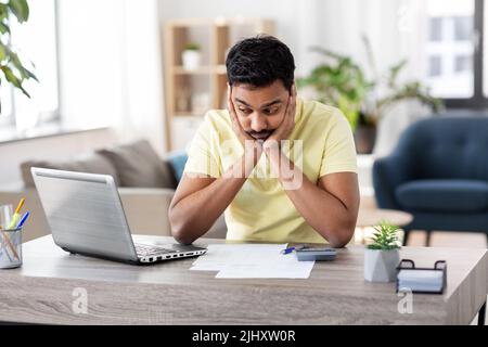 Mann mit Rechner und Papier, der zu Hause arbeitet Stockfoto