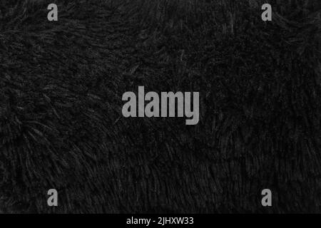 Kunstpelz schwarze Wolle abstraktes Muster Natur Haut weich warm flauschig Hintergrund dunkel künstliche Textur. Stockfoto