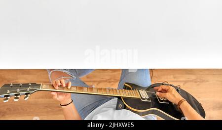 Junger Mann spielt Gitarre und sitzt am Tisch Stockfoto