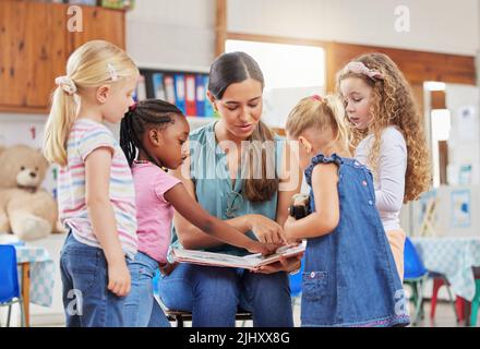 Dies ist einfach die beste Art und Weise für kleine Kinder zu lernen. Eine junge Frau, die ihren Vorschulstudenten vorliest. Stockfoto