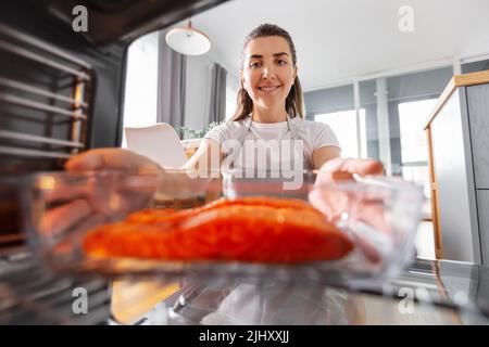 Frau, die in der heimischen Küche im Ofen kocht Stockfoto