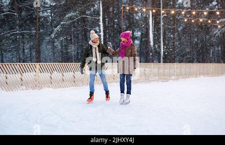 glückliches Paar halten die Hände auf Eisbahn Stockfoto