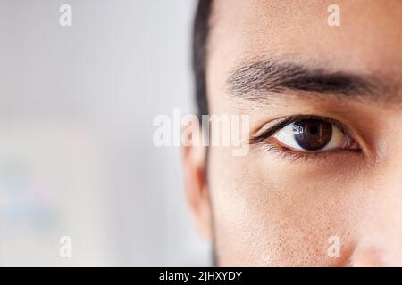 Nahaufnahme eines hübschen jungen Mannes mit gemischter Rasse, der bei der Arbeit in einem Bürojob steht. Junger hispanischer Mann mit natürlich langen Wimpern und ordentlich Stockfoto