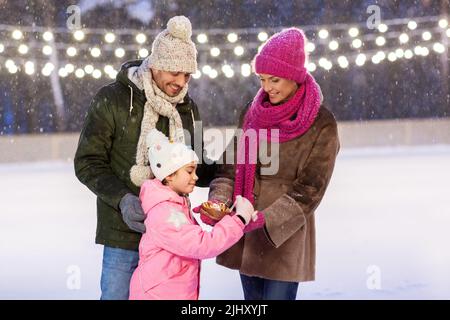 Glückliche Familie, die Pfannkuchen auf der Eislaufbahn isst Stockfoto