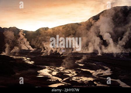 Eine dramatische Sonnenuntergangsszene von El Tatio Geyser mit starkem Rauch über dem Feuchtgebiet in Chile Stockfoto