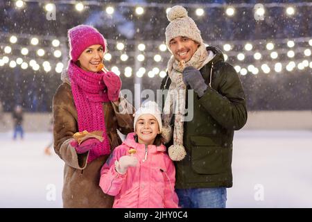 Glückliche Familie, die Pfannkuchen auf der Eislaufbahn isst Stockfoto