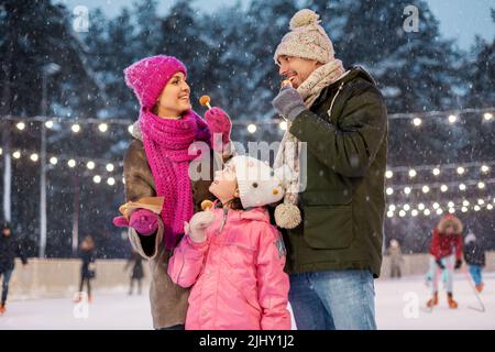 Glückliche Familie, die Pfannkuchen auf der Eislaufbahn isst Stockfoto