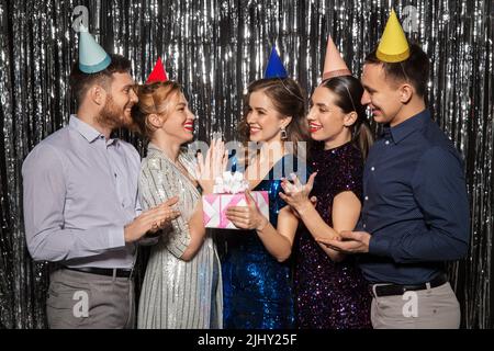 Glückliche Freunde in Partyhüten mit Geburtstagsgeschenk Stockfoto