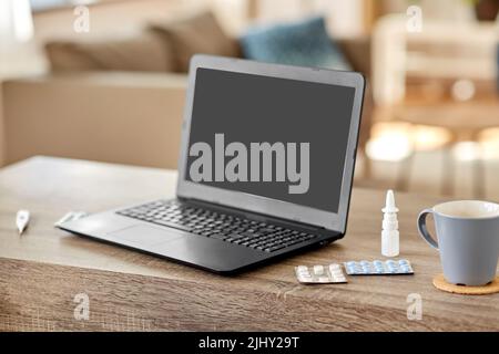 Laptop-Computer, Drogen und Tasse auf dem Tisch zu Hause Stockfoto