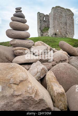 Eine kleine felsige Kaimne auf der felsigen Meereswand am Minard Beach mit den Resten von Minard Castle, die im Hintergrund, County Kerry, Irland, entkokettet wurden Stockfoto