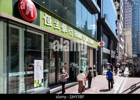 Fußgänger werden gesehen, wie sie die Straße vor der Filiale der Hang Seng Bank in Hongkong überqueren. Stockfoto