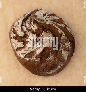 Hausgemachtes frisch gebackenes traditionelles Roggenbrot isoliertes Backpapier, Draufsicht, runder Volllaib rustikalen Bio-Getreidebreides mit knuspriger Crus Stockfoto