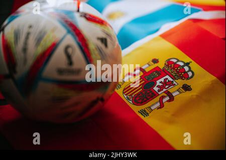 KATAR, DOHA, 18. JULI 2022: Spanische Nationalflagge und offizieller Adidas-Fußball-WM Al Rihla. Und Logo der FIFA Fußball-Weltmeisterschaft in Katar 2022 Stockfoto