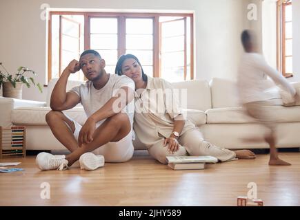 Frustriert gestresste afroamerikanische Eltern, die Kopfschmerzen haben, fühlen sich müde genervt über laute aktive Kinder, die zu Hause spielen, verärgert gestörte gemischte Rasse Stockfoto