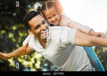 Fröhlicher Vater trägt Tochter auf dem Rücken. Kleines Mädchen und Dädchen spielen Flugzeug. Kind, das vorgibt zu fliegen, während es Huckepack-Fahrt am bekommt Stockfoto