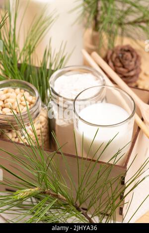 Zedernmilch, Mehl, Nüsse im Glas Geschirr in Holzkiste, Kegel und Äste. Nicht milchfreie Alternativmilch. Bio-Milchaustauschstoff. Gesundes Getränk. Schließen Sie U Stockfoto