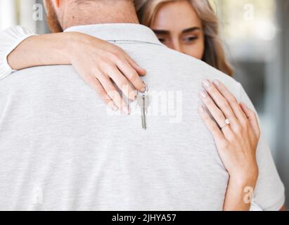 Nahaufnahme der glücklichen Frau umarmte Mann, während die Schlüssel nach dem Kauf des ersten Hauses halten. Ehepaar zieht in ein neues Haus oder eine neue Wohnung um. Frisch verheiratetes Paar zieht um Stockfoto