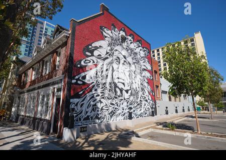 Ein riesiges Wandbild auf einer roten Ziegelwand, das ein Porträt eines legendären Indianerhäuptlings zeigt. Im Chinatown-Viertel der Innenstadt von Oakland, Kalifornien. Stockfoto