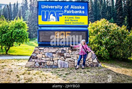 06-27-2022 Fairbanks Alaska USA Frau, die an einem Temperaturschild an der University of Alaska feststeht Fairbanks Zeichen, das ungewöhnlich heiße 80F Grad zeigt, wo Stude Stockfoto