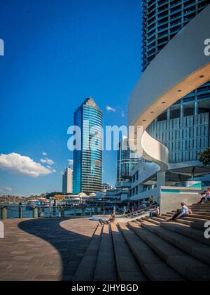 08-14 2014 Brisbane Australien- Menschen, die auf einer Treppe in der Nähe des Flusses sitzen, mit Blick auf die CBD-Wolkenkratzer und die Architektur in Brisbane Stockfoto