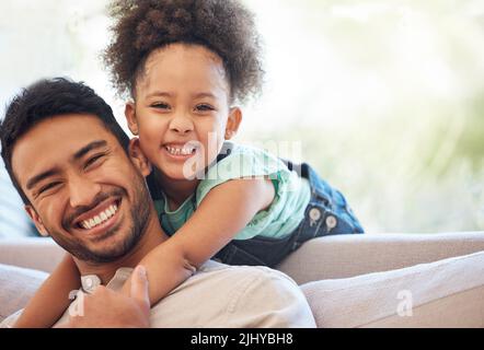 Wir haben eine besondere Bindung. Beschnittenes Porträt eines hübschen jungen Mannes und seiner entzückenden kleinen Tochter im Wohnzimmer zu Hause. Stockfoto