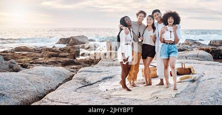 Eine Gruppe von Freunden genießt ihre Zeit zusammen und trinkt einige alkoholische Getränke am Strand Stockfoto