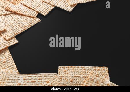 Ein Foto von Matza oder Matza-Stücken auf schwarzem Hintergrund. Matza für die jüdischen Passahfeiertage. Platz für Text, Platz zum Kopieren Stockfoto