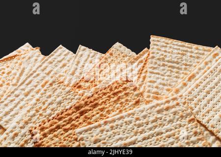 Ein Foto von Matza oder Matza-Stücken auf schwarzem Hintergrund. Matza für die jüdischen Passahfeiertage. Platz für Text, Platz zum Kopieren Stockfoto