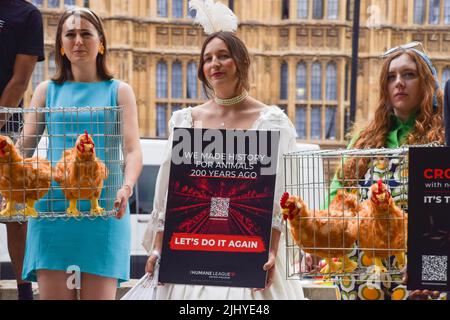 London, England, Großbritannien. 21.. Juli 2022. Die Demonstranten halten Käfige mit Plüschhühnchen in der Hand. Aktivisten der Humane League UK versammelten sich vor dem Parlament, um die Regierung aufzufordern, engen, grausamen Käfigen ein Ende zu setzen, in denen eierlegende Hühner häufig gehalten werden. Der Protest markiert 200 Jahre seit dem ersten Tierschutzgesetz Großbritanniens, bei dem mehrere Aktivisten historische Kleidung trugen. (Bild: © Vuk Valcic/ZUMA Press Wire) Stockfoto