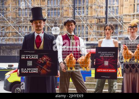 London, England, Großbritannien. 21.. Juli 2022. Demonstranten halten Plakate und Käfige mit Plüsch-Hühnerspielzeug. Aktivisten der Humane League UK versammelten sich vor dem Parlament, um die Regierung aufzufordern, engen, grausamen Käfigen ein Ende zu setzen, in denen eierlegende Hühner häufig gehalten werden. Der Protest markiert 200 Jahre seit dem ersten Tierschutzgesetz Großbritanniens, bei dem mehrere Aktivisten historische Kleidung trugen. (Bild: © Vuk Valcic/ZUMA Press Wire) Stockfoto