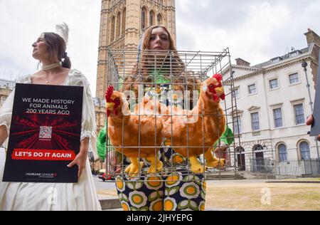 London, England, Großbritannien. 21.. Juli 2022. Ein Protestler hält einen Käfig mit Plüsch-Hühnchen-Spielzeug. Aktivisten der Humane League UK versammelten sich vor dem Parlament, um die Regierung aufzufordern, engen, grausamen Käfigen ein Ende zu setzen, in denen eierlegende Hühner häufig gehalten werden. Der Protest markiert 200 Jahre seit dem ersten Tierschutzgesetz Großbritanniens, bei dem mehrere Aktivisten historische Kleidung trugen. (Bild: © Vuk Valcic/ZUMA Press Wire) Stockfoto