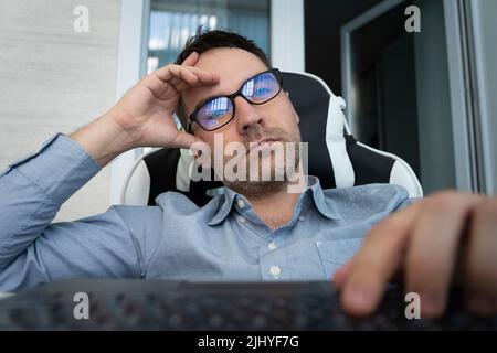 Müde gelangweilter Mann Mitarbeiter am Schreibtisch sitzt hat keine Motivation zu arbeiten. Uninteressante langweilige Arbeit im Bürokonzept. Stockfoto