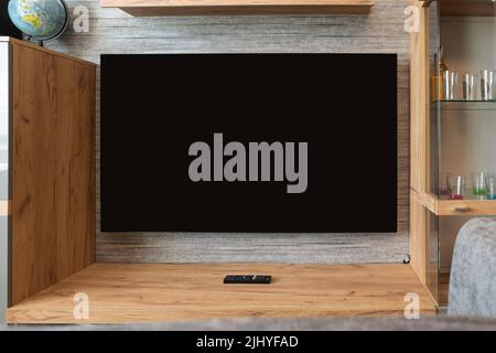 Moderner Fernseher auf dem Ständer im Wohnzimmer. Schwarzer Bildschirm für die Veröffentlichung von Informationen Stockfoto