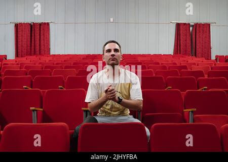 Ein einsamer Zuschauer in einem leeren Theater beobachtet aufmerksam das Stück Stockfoto