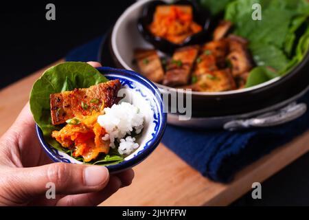 Asiatisches Speisekonzept hausgemachtes koreanisches gegrilltes Schweinebauch-BBQ Samgyeopsal-gui mit Kimchi und Shiso und Salat auf schwarzem Hintergrund mit Kopierfläche Stockfoto