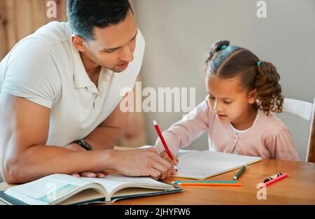 Vater hilft seiner Tochter bei ihren Hausaufgaben. Papa lehrt Tochter lesen und schreiben während der Homeschool-Klasse. Kleines Mädchen, das zu Hause mit Tutor sitzt Stockfoto