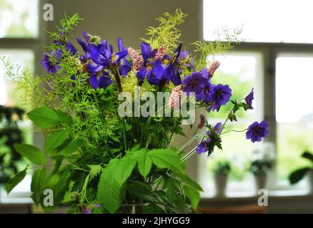 Haufen Wiesenkrane-Rechnung in einer Vase als Dekoration für eine Hochzeitsfeier oder Zeremonie. Ein wunderschöner Blumenstrauß aus violetten Blumen als Dekor bei einer Veranstaltung Stockfoto