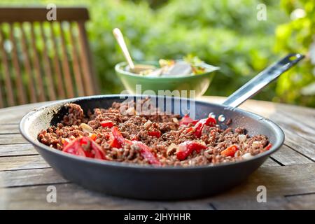 Eine köstliche Mahlzeit mit gekochtem Rinderfleisch und Pfeffergemüse. Chili con Carne Eintopf, serviert zum Abendessen in einem Restaurant im Freien. Texturdetails von Stockfoto